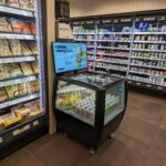 Kühldisplay Polarlight mit Getränken von yfood umgeben von vollen Regalen in einem Supermarkt